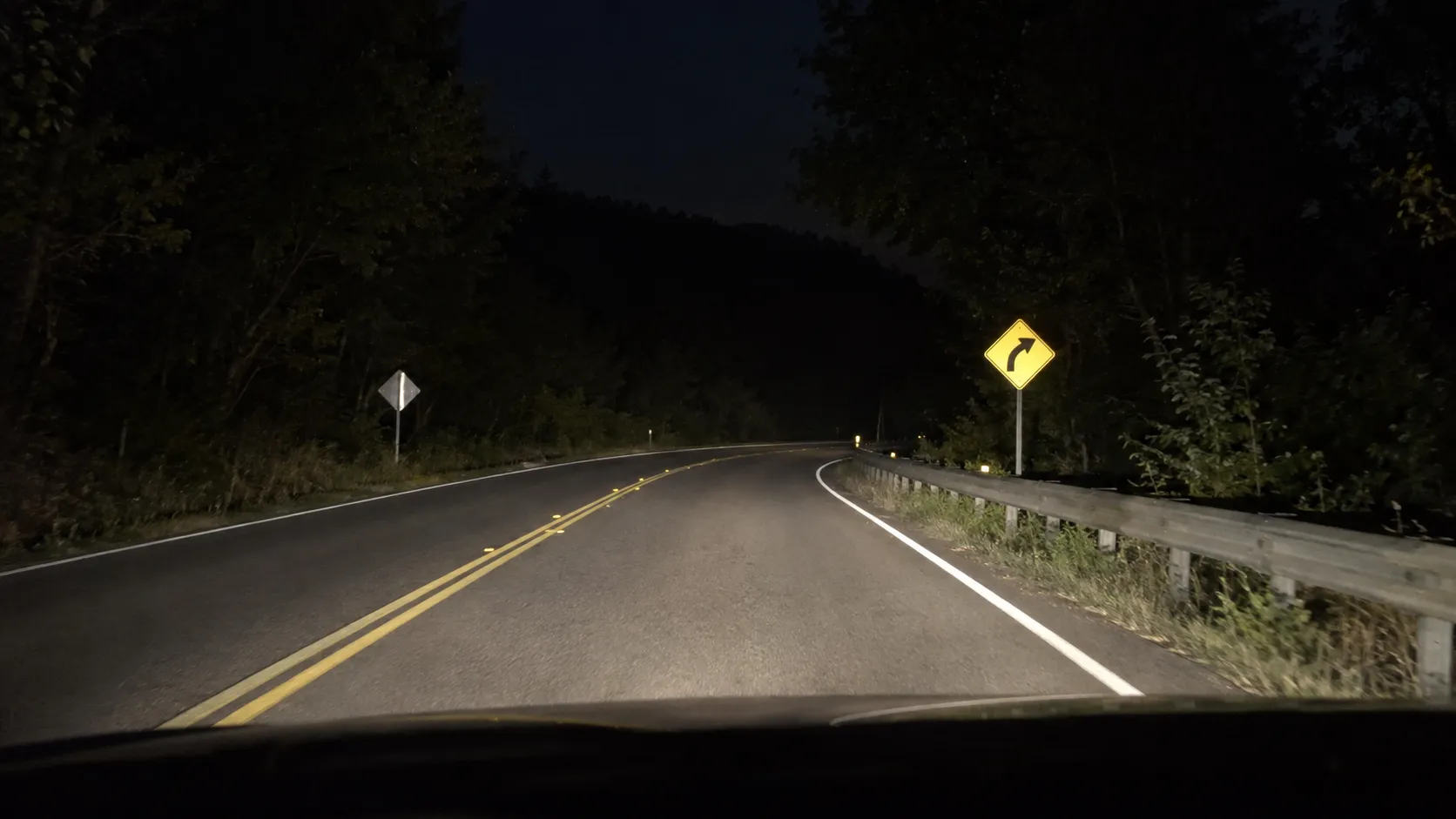 Reflective traffic signs inspected under vehicle headlights at night.webp